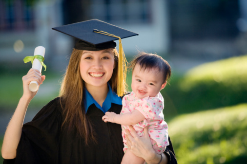 Pretty Asian woman graduate wearing cap and gown holding diploma and baby